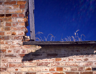 Wooden window frame and the brick wall in an abandoned derelict and partially fallen down old rural...
