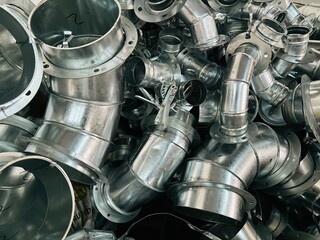 Stack of galvanized steel duct pipes and fittings in an industrial warehouse for ventilation system...