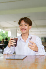 Non binary university student sitting in college campus using phone