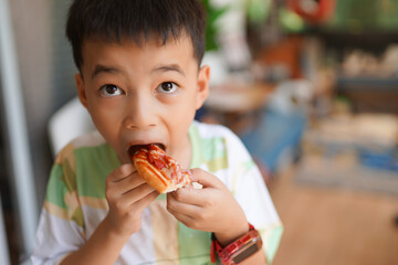 Little boy happily eating  sandwich with a smile