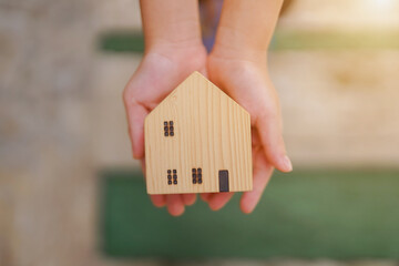 Hand holding a small house representing real estate and property investment concept