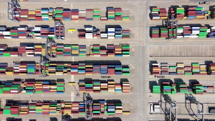 Aerial top down hyper lapse timelapse of busy cargo containers port terminal heavy cranes and trucks in Felixstowe England UK