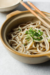 overhead view of soy sauce noodles with sliced green onions, top view of spring noodles with soy sauce broth topped with green onions in a claypot