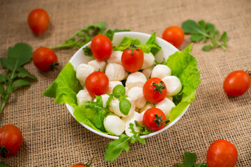 mini mozzarella in white bowl with herbs and cherry tomatoes