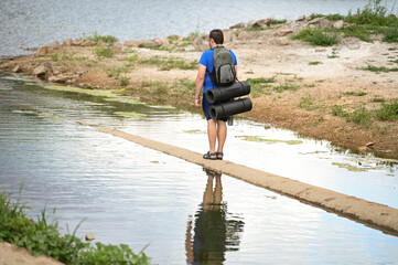 a tourist with a backpack walks along the river beach