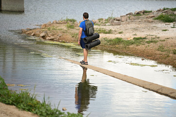 a tourist with a backpack walks along the river beach