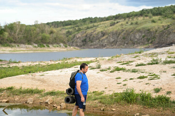 a tourist with a backpack walks along the river beach