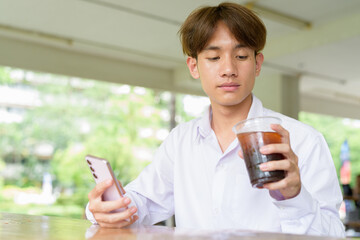Non binary university student sitting in college campus