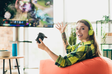 Enthusiastic gaming session with a cheerful young woman wearing headphones and enjoying an exciting...