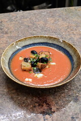 Tomato soup with black olives and croutons in restaurant