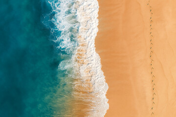 Aerial view of a sandy beach with turquoise ocean waves and footprints