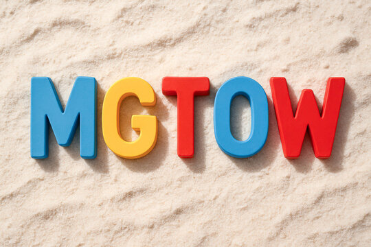 The acronym "MGTOW" is spelled out using multicolored letters against a textured, sand-like beige background, symbolizing independence and solitude.