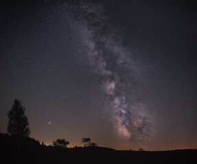 Milky Way galaxy over silhouetted landscape.
