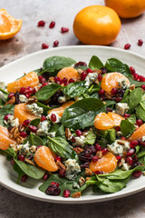 An appetizing festive salad of fresh spinach, tangerine, pomegranate and pine nuts on a plate. 
