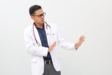 Displeased asian adult doctor man wearing doctor's suit, white background keeps hands to sideways...
