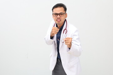 Adult asian man wearing doctor 's suit, stethoscope ready to fight with fist defense gesture, angry...