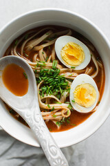 Overhead view of spicy noodle soup in a white bowl, top view of noodles in a spicy broth with scallions
