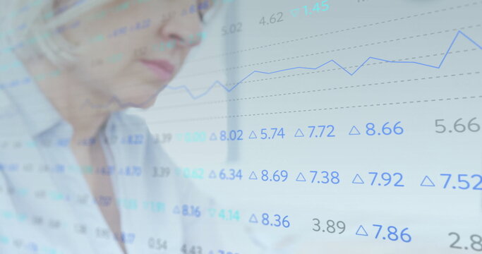 Senior analyst examining financial data overlay, blue line graph, delta symbols at desk