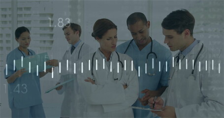 Staff in uniforms reviewing patient charts with tablet, clipboard and stethoscopes in hospital hall