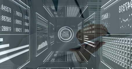 Interacting analyst tapping stylus on tablet at office workstation, translucent holographic panels