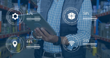 Warehouse worker monitoring digital order status graphics in warehouse aisle, with tablet