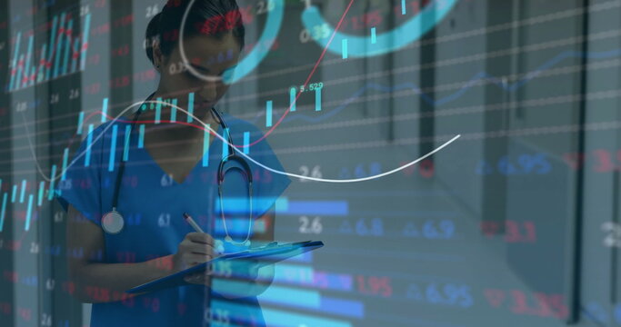 Clinician writing notes on clipboard in hospital corridor, with scrubs, stethoscope, digital charts