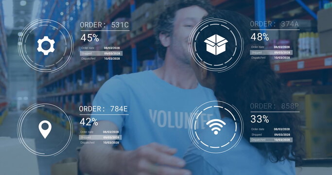 Two volunteers wearing light blue shirts hugging in warehouse with boxes and digital overlays