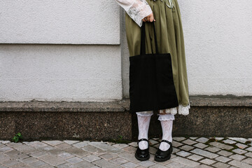Young white woman holding black eco bag on arm shoulder or hand, street wall at background. city...