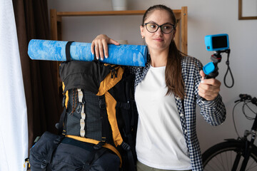 Young woman traveler hiker with backpack ready to mountain hiking taking picture with action camera...