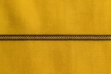 A close-up of a vibrant yellow fabric with a distinctive black border, featuring an intricate zigzag pattern