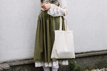 Young white woman holding black eco bag on arm shoulder or hand, street wall at background. city...