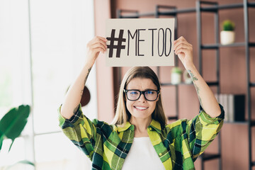 Young woman holding a sign supporting activism in a modern indoor setting with a bright environment