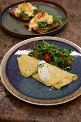 A freshly served omelette with arugula and cherry tomato salad on a rustic ceramic plate