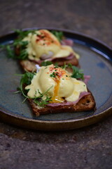 Eggs benedict with ham, rucola and cheese, closeup, serving breakfast menu