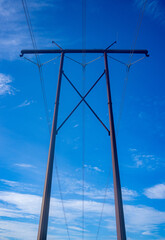 Industrial power lines on pilons on a blue sky
