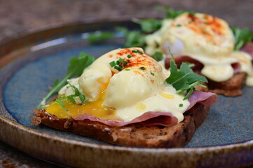 Eggs benedict with ham, rucola and cheese, closeup, serving breakfast menu