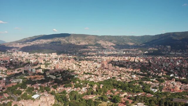Drone shot of Comuna 13 in Medell&iacute;n, Colombia, featuring colorful murals, vibrant streets, and tourist activity. An iconic area known for its social transformation and urban street art.