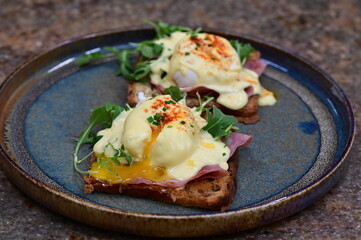 Eggs benedict with ham, rucola and cheese, closeup, serving breakfast menu