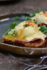 Eggs benedict with ham, rucola and cheese, closeup, serving breakfast menu