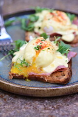 Eggs benedict with ham, rucola and cheese, closeup, serving breakfast menu