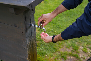 Male Hands Washing or Drinking Fresh Water from Outdoor Tap. Essential Hygiene and Hydration in...