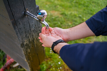 Male Hands Washing or Drinking Fresh Water from Outdoor Tap. Essential Hygiene and Hydration in...