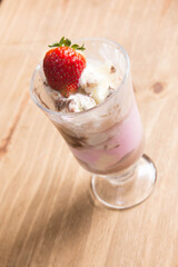 strawberry milkshake with ice cream in glass on wood table