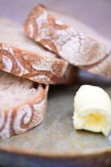 Sliced sourdough bread with butter, served on a rustic surface.