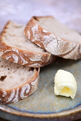 Sliced sourdough bread with butter, served on a rustic surface.