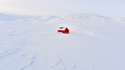 Solitary Red Cabin Amidst a Snowy Landscape: A vibrant red cabin stands starkly against the expansive, snow-covered terrain, evoking a sense of solitude and isolation amidst the cold.