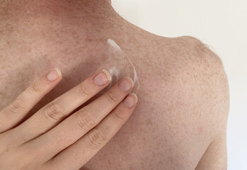 A woman's hand spreads cream on a man's body