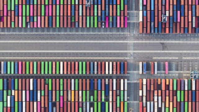 [Port of Oakland], United States - 07 April 2025: Aerial view of vibrant shipping containers lined in neat rows, their colorful surfaces creating a striking contrast against the stark gray asphalt.