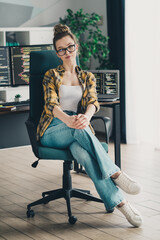 Young female programmer working on a computer at a home office workspace, wearing glasses and...