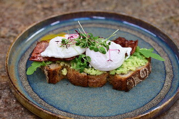 Avocado Toast with Poached Eggs, Bacon and Microgreens – Gourmet Breakfast Close-Up
